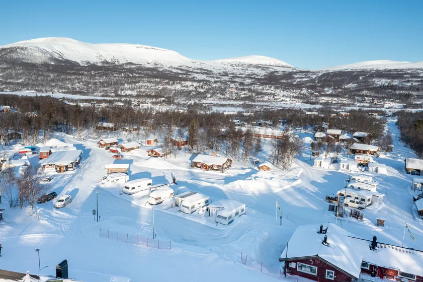Flygfoto över camping med husvagnar, stugor och servicehus.