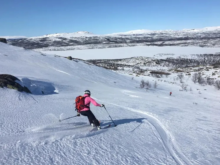 Två personer som åker offpist på fjällsluttning.