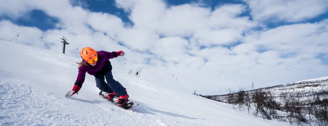 Tjej åker snowboard nedför en backe