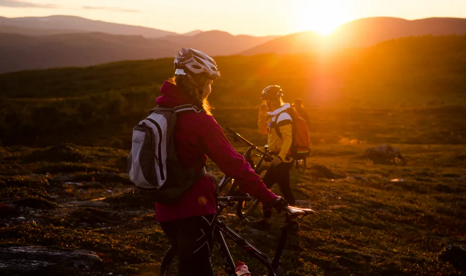 Två kvinnor cyklar mtb i solnedgång