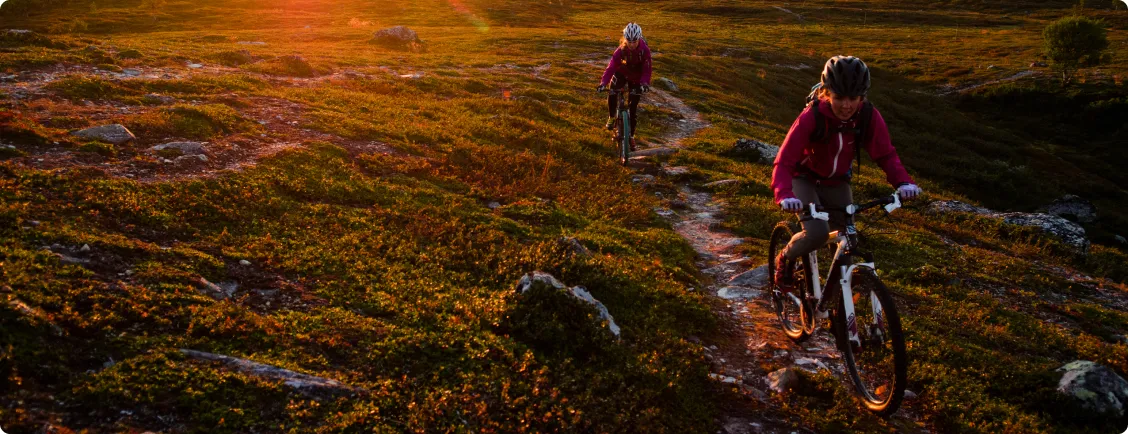 Två kvinnor cyklar mtb på stig i fjällen