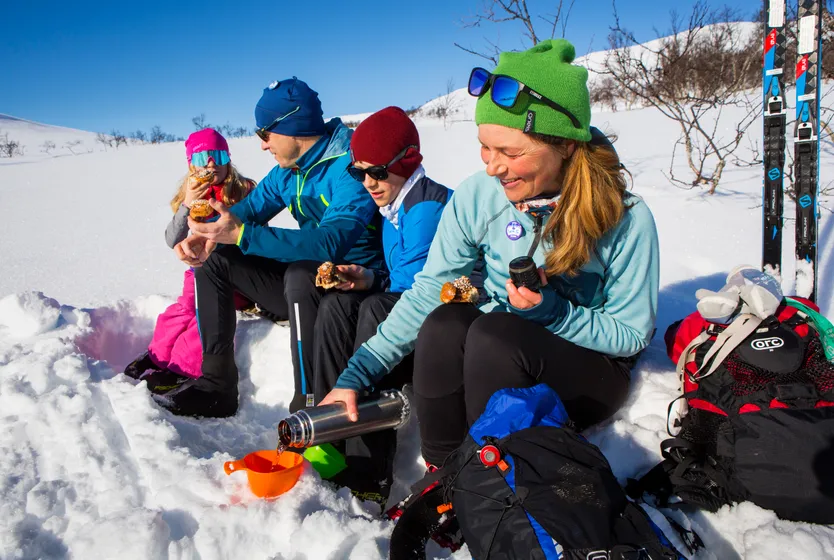 Familj fikar på fjället i en snögrop