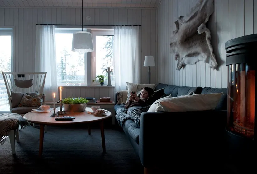 Inomhusbild med mysig soffgrupp, tända ljus och braskamin i förgrunden.
