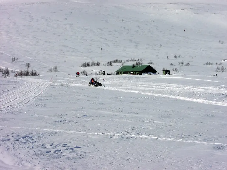 Skoter på fjället, framför stuga.