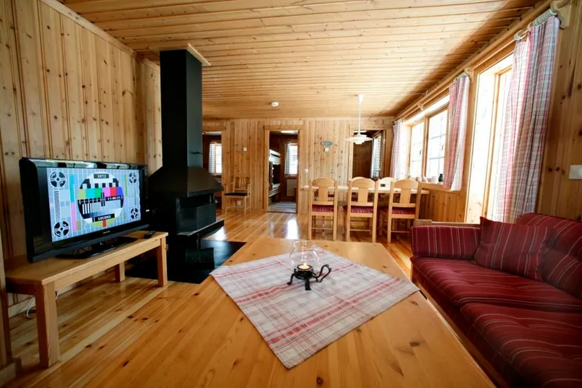 Stugmiljö med soffgrupp, braskamin och matplats.